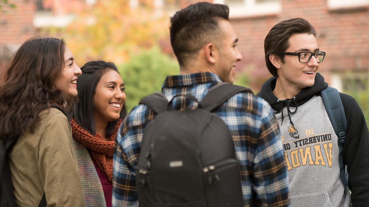Four students laughing outside on campus
